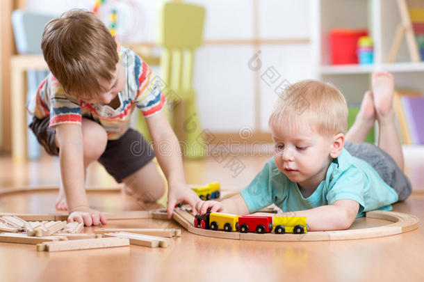 可爱的孩子们玩木火车。 蹒跚学步的孩子玩积木和火车。 男孩在家建造玩具铁路或