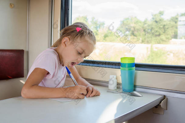 女孩在二等火车车厢里的一张纸上画一支笔
