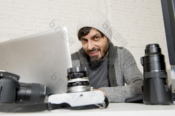 有吸引力的新闻摄影师男子工作与笔记本电脑和桌子充满摄影器材