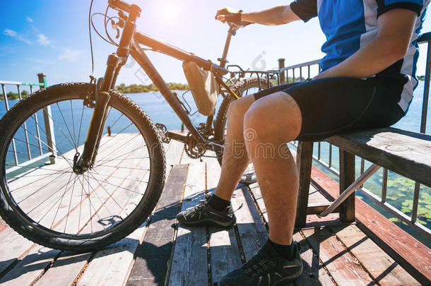 骑自行车的人在河边的梨子里放松。 阳光明媚的夏天炎热的一天