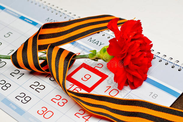 鲜红色的康乃馨，用乔治丝带包裹，放在日历上，镶有5月9日的日期