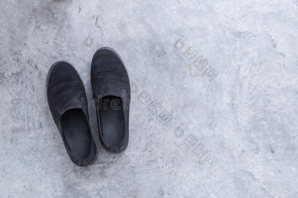 一双旧的脏鞋在水泥地板上，从角落里浅色。
