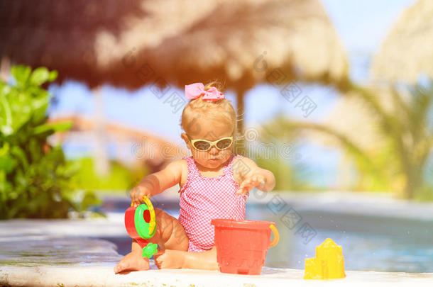 可爱的蹒跚学步的女孩在海滩的游泳池里玩耍