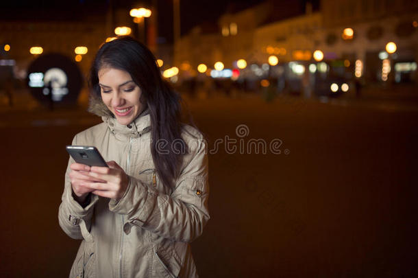 兴高采烈的女人使用她的智能手机和微笑的好消息。快乐的女人在智能手机上打字