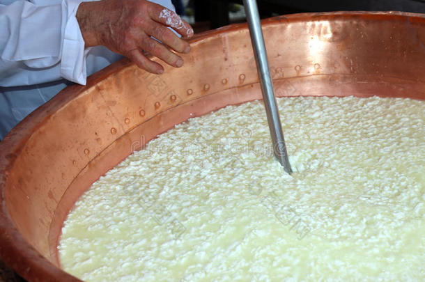 奶酪制造商把卷发搅拌到锅里做奶酪
