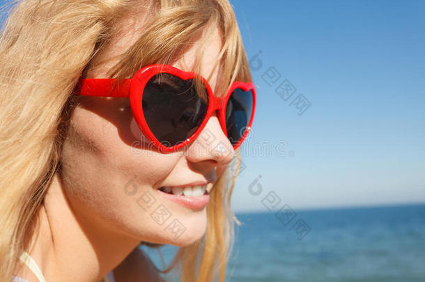 戴着<strong>红色</strong>太阳镜的女孩在<strong>海边</strong>放松。
