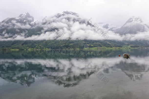 船在湖上，背景上有山和云，水面上有倒影，挪威