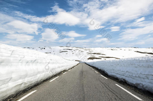 沥青路穿过群山，有很多雪，夏天的挪威。 国家旅游路线极光。