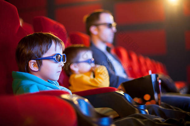 父亲和两个孩子，男孩，在电影院看卡通电影