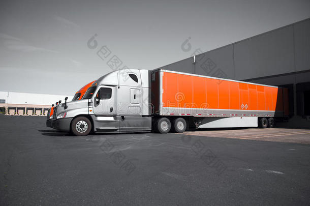 明亮的现代橙色和灰色半卡车在仓库卸货