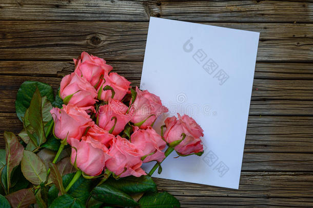 木桌上有十几朵粉红色的玫瑰和纸