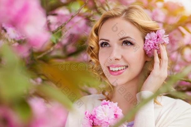 金发女人，卷曲的头发映衬着蓝色的粉红色树