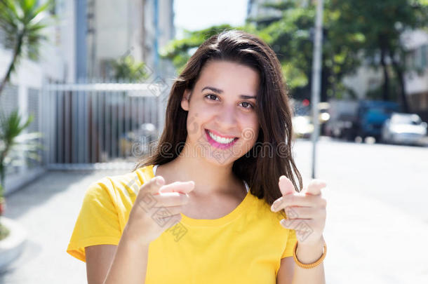 白种女人穿着黄色衬衫在城市里指着相机