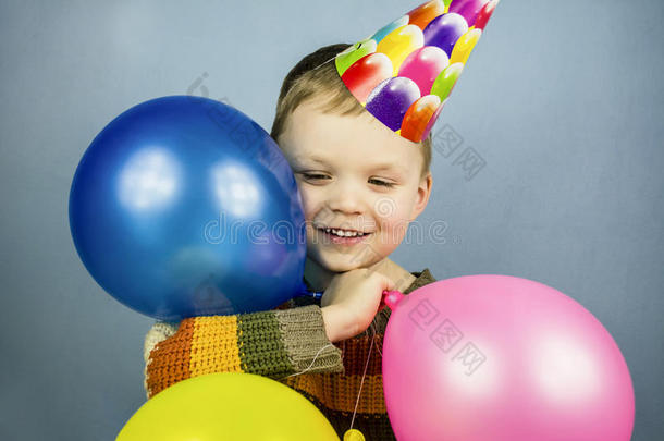 戴着庆祝帽的男孩拿着气球