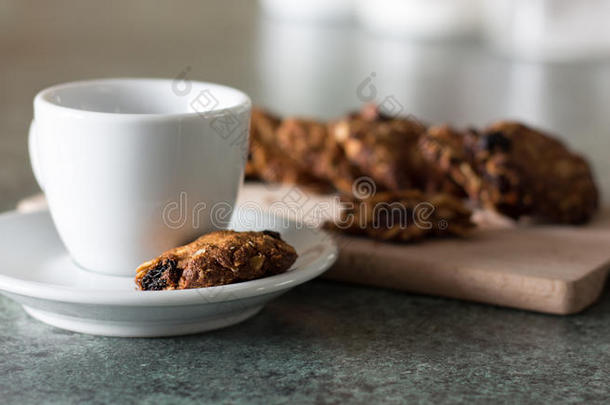 手工谷物饼干与白色咖啡杯在木制切割板上
