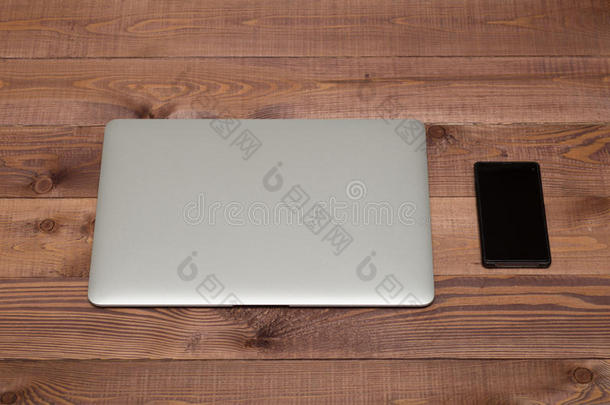 棕色木桌上的银色笔记本电脑和智能手机