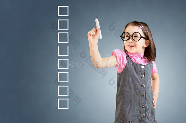 <strong>可爱</strong>的小女孩穿着商务礼服，在一些空白的清单框上写字。 <strong>蓝色背景</strong>。