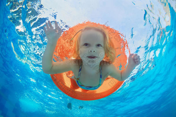 孩子在游泳池的橙色充气管上游泳