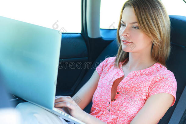 商务旅行：忙碌的女商人带着笔记本电脑在车里
