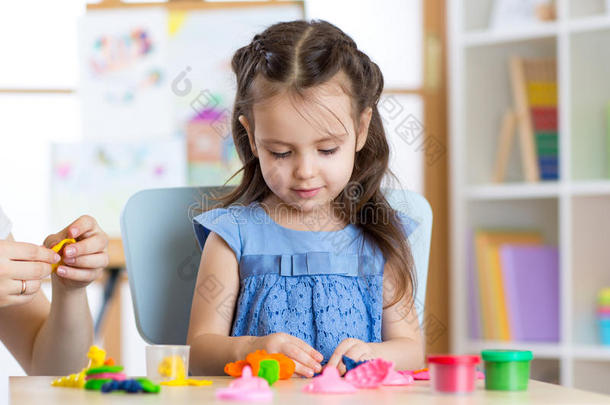 可爱的小女孩在桌子上用塑料做模具
