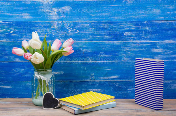 蓝色木<strong>桌背景</strong>上五颜六色的郁金香花和黄色的书。 复制空间