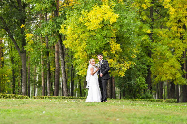 一对穿着婚纱的夫妇带着一束花，新娘和新郎在户外
