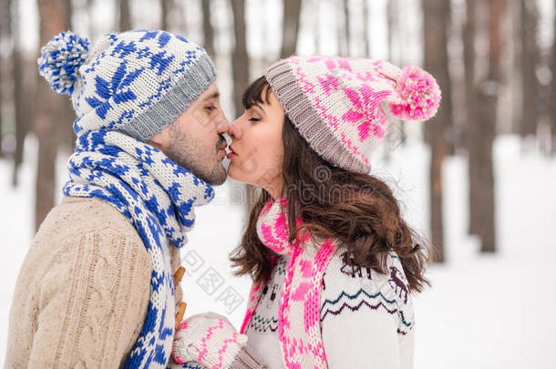 一对相爱的夫妇在冬天的森林里穿着毛衣特写接吻