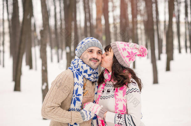 冬天在户外亲吻她男朋友的脸颊。 穿着舒适的保暖衣服，针织帽子和手套。 冬季约会骗局