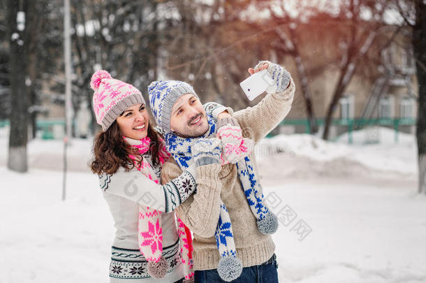 一对相爱的夫妇在冬天的户外用毛衣、围巾和手套自拍