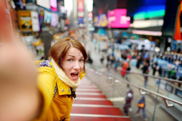 美丽的年轻女人在<strong>时代广场</strong>用她的智能手机自拍
