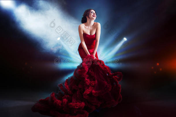 美丽的黑发模特女人穿着晚红礼服。 美丽时尚，豪华化妆和发型。 黑暗的背景，光明