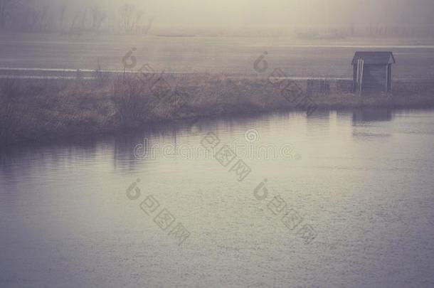 一个雾蒙蒙的下午，在池塘上的一座小建筑物