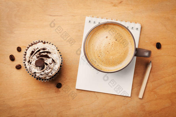 咖啡杯与纸杯蛋糕，<strong>笔记本</strong>和铅笔在乡村桌子上从<strong>上面</strong>，早上好或有一个美好的一天概念