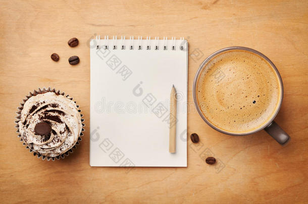 咖啡杯与纸杯蛋糕，笔记本和铅笔在乡村桌子上从上面，早上好或有一个美好的一天概念