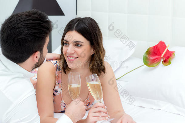 一对夫妇在床上喝起泡酒。