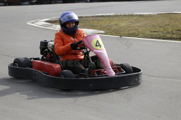 女孩正在操场上的赛道上以速度驾驶卡丁车。