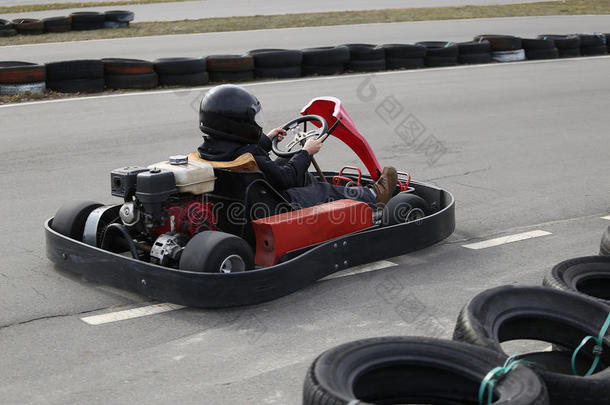 男孩正在操场上的赛道上以速度驾驶卡丁车。