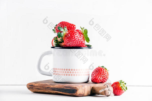 新鲜成熟的红色草莓，乡<strong>村风</strong>格的搪瓷杯，在白色背景的乡村木板上