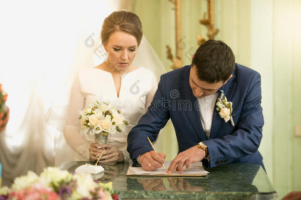 在登记处签署婚<strong>礼</strong>合同的年轻新郎的特写