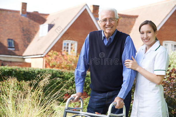 照顾者帮助老人用步行架在花园里散步