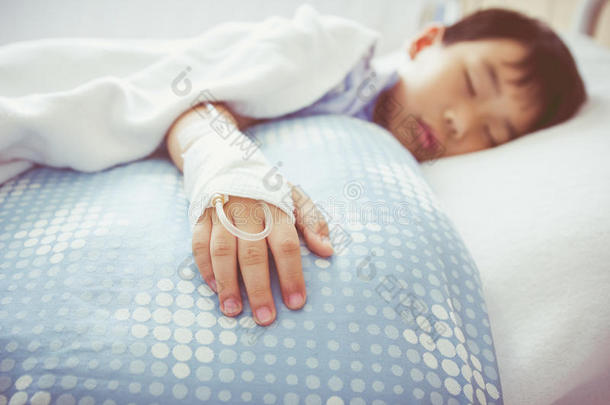 亚洲男孩躺在病床上用生理盐水静脉注射(Iv)。 健康