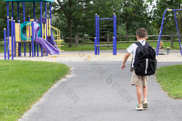 背着<strong>书包</strong>和书在公园里散步的孩子