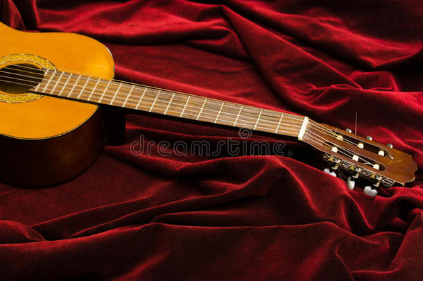 古典尼龙吉他躺在红色天鹅绒织物上，艺术乐器呈现