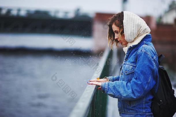 雨中码头上的女孩用手敲打栏杆，形成飞溅