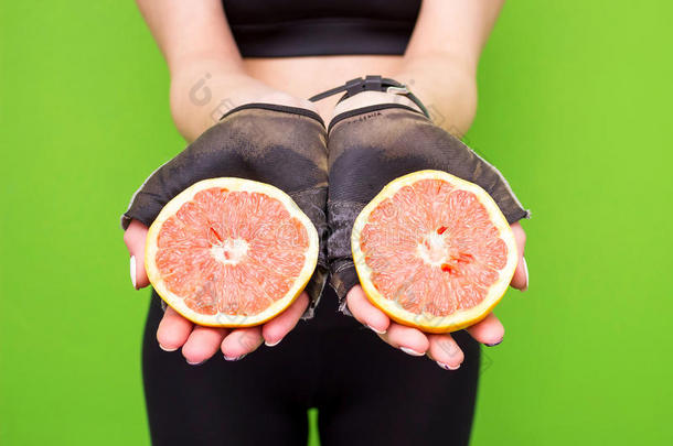 年轻的黑发健身妇女抱着新鲜的粉红色葡萄柚的滑稽肖像。 健康的饮食生活方式和减肥理念。