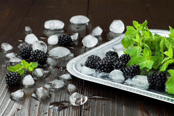 黑莓和薄荷与冰在银色托盘上的黑暗乡村木桌。 暑期背景