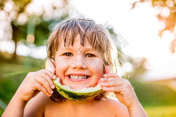 可爱的小女孩在阳光明媚的夏天花园里吃西瓜