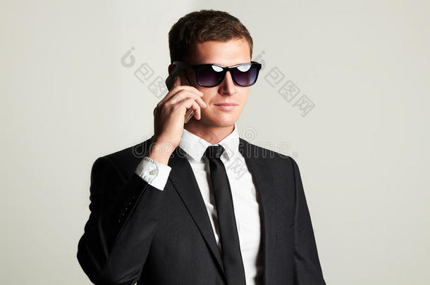 商人在电话里。 穿着西装和太阳镜的英俊男人