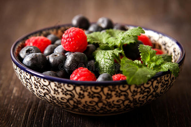 蓝莓和覆盆子在一个有黑色背景的盘子里