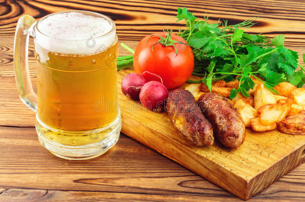 烤肉香肠，油炸土豆，新鲜农产品和一杯啤酒在木板上